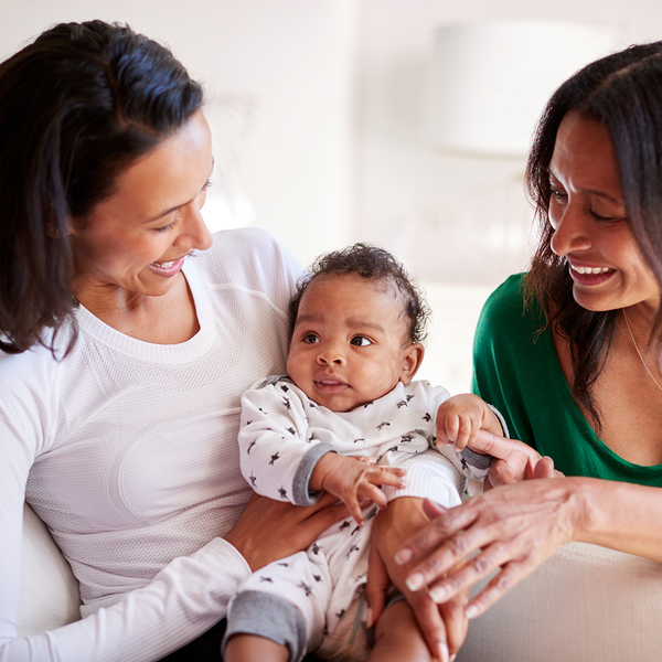 Two mothers smiling with a baby at a support group